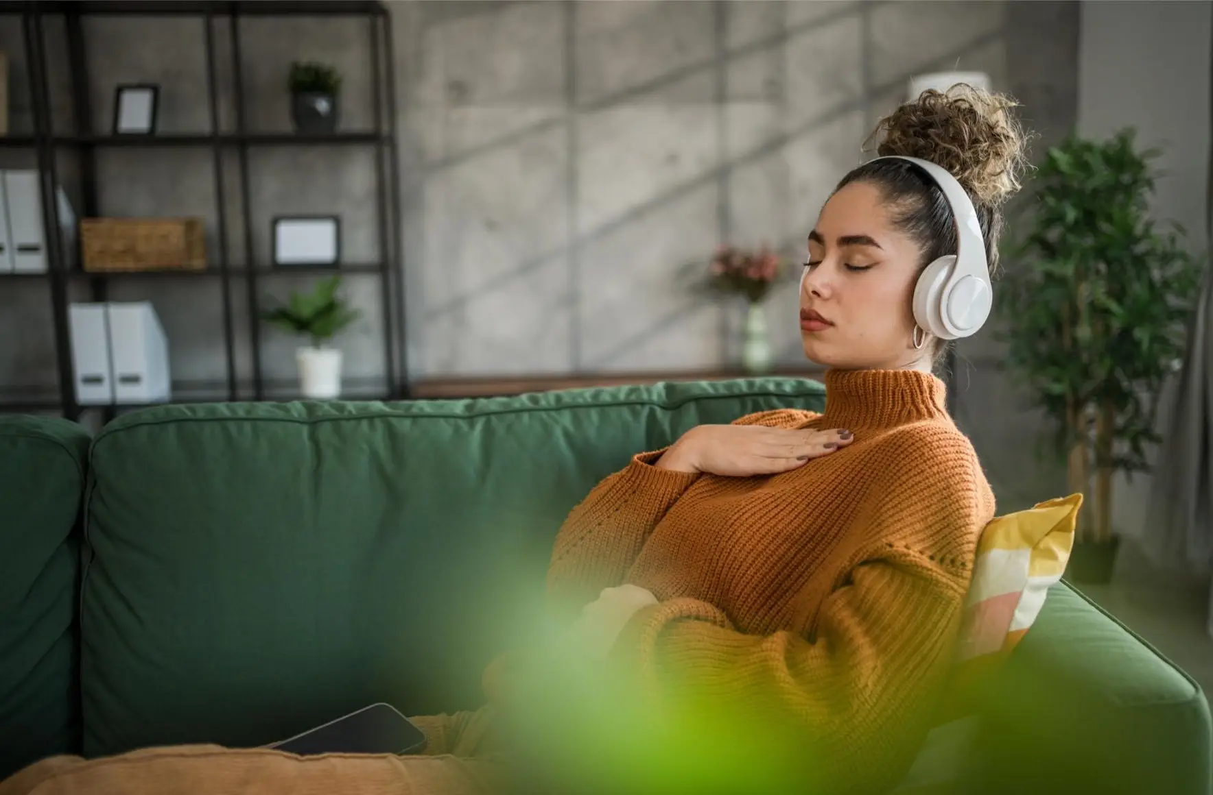 A young beautiful woman practices guided meditation in the living room on her sofa