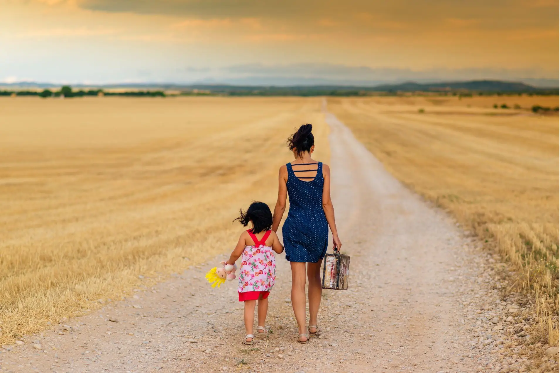 mother and child talking hand-in-hand down a dirt track.