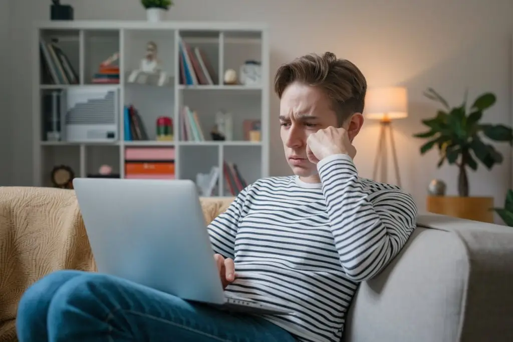 A person sitting on down in their living room searching online for a therapist